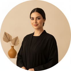 Circular portrait of Maryam Ismat, a young woman with a gentle smile, wearing a royal black AMIRA abaya set, against a warm c